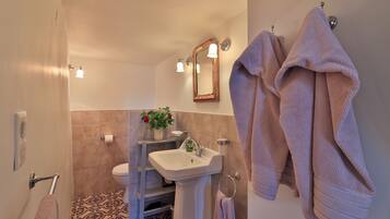 Baño con lavamanos, espejo, toallero y baldosas de suelo con diseño.