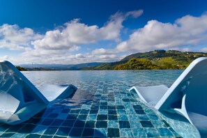 Una piscina con agua azul cristalina y vista a un paisaje montañoso al fondo.
