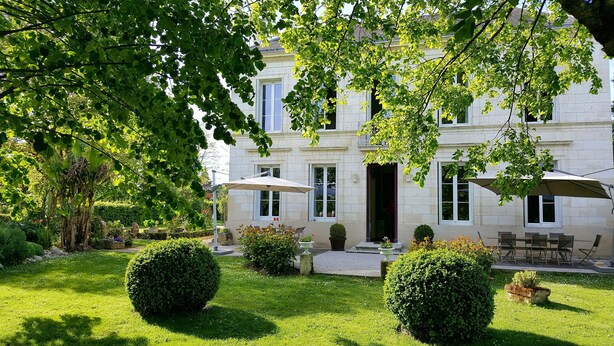 A courtyard with a stone building, outdoor seating, and well-maintained greenery. - L'escale de Bel Air (Gauriac)
