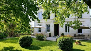 A courtyard with a stone building, outdoor seating, and well-maintained greenery. - L'escale de Bel Air (Gauriac)