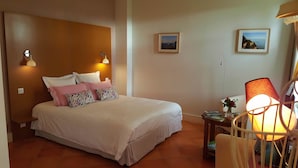 A bedroom with a bed, pillows, a nightstand, a lamp, and two framed pictures on the wall. - L'escale de Bel Air (Gauriac)