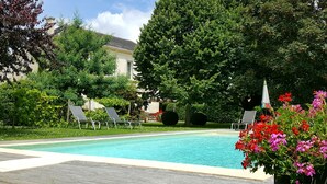 A swimming pool with lounge chairs, surrounded by lush greenery and a building in the background. - L'escale de Bel Air (Gauriac)