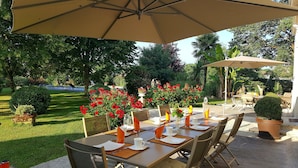 An outdoor dining area with tables set for two, surrounded by lush greenery and red flowers. - L'escale de Bel Air (Gauriac)