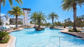Ein Pool mit Liegestühlen und Palmen, umgeben von Gebäuden.