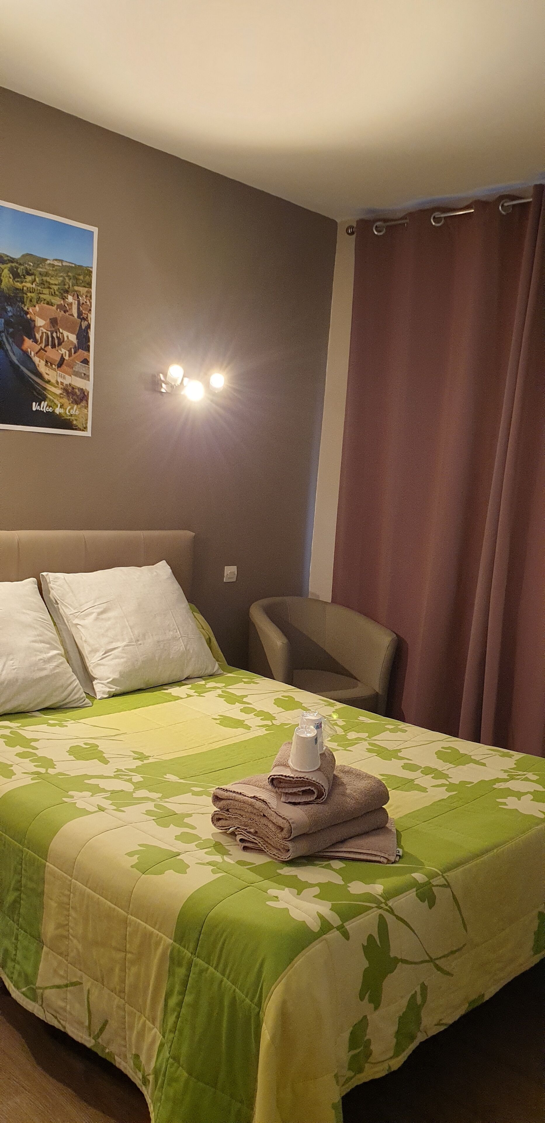 Una habitación de hotel con una cama, una silla, una lámpara de pared y un cartel.