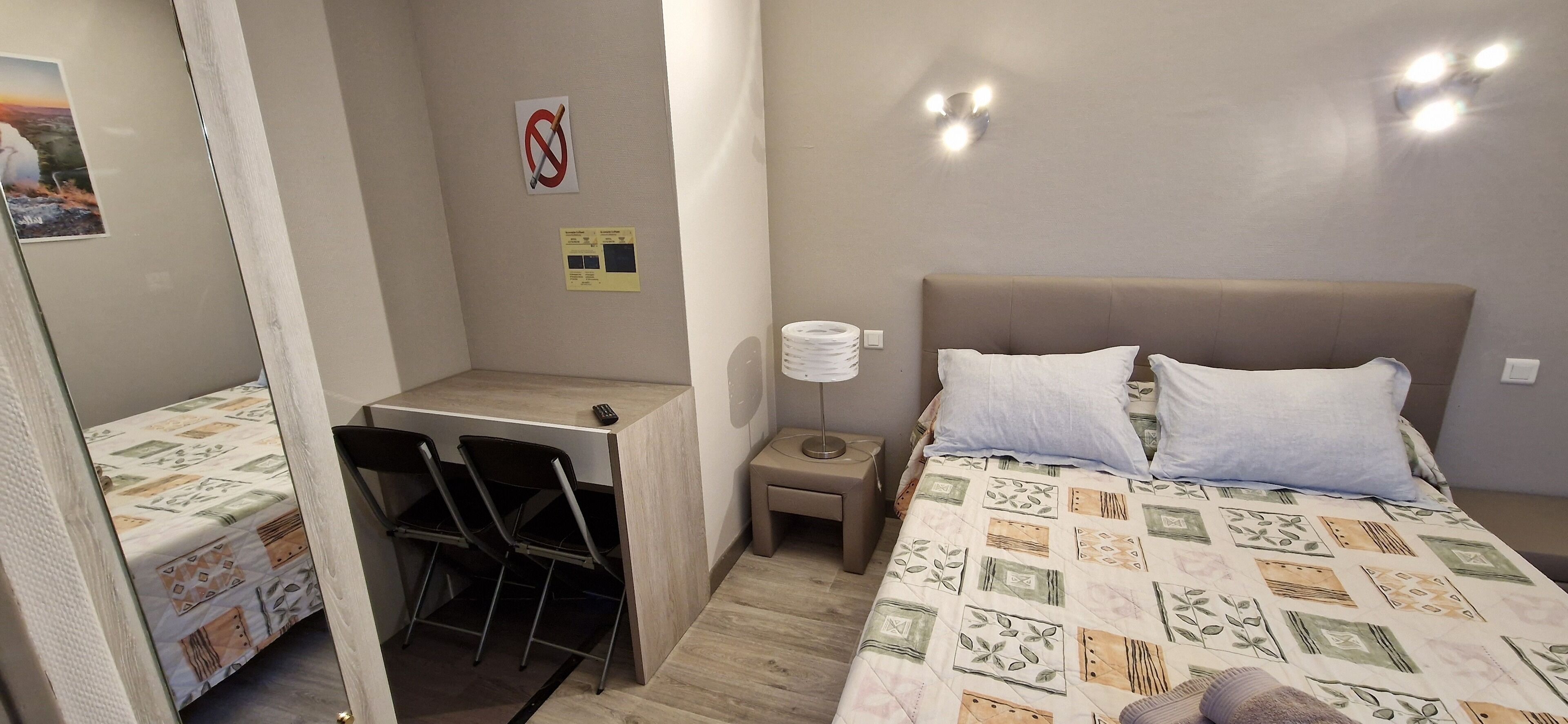 Une petite pièce comprenant un lit, un bureau et deux chaises.