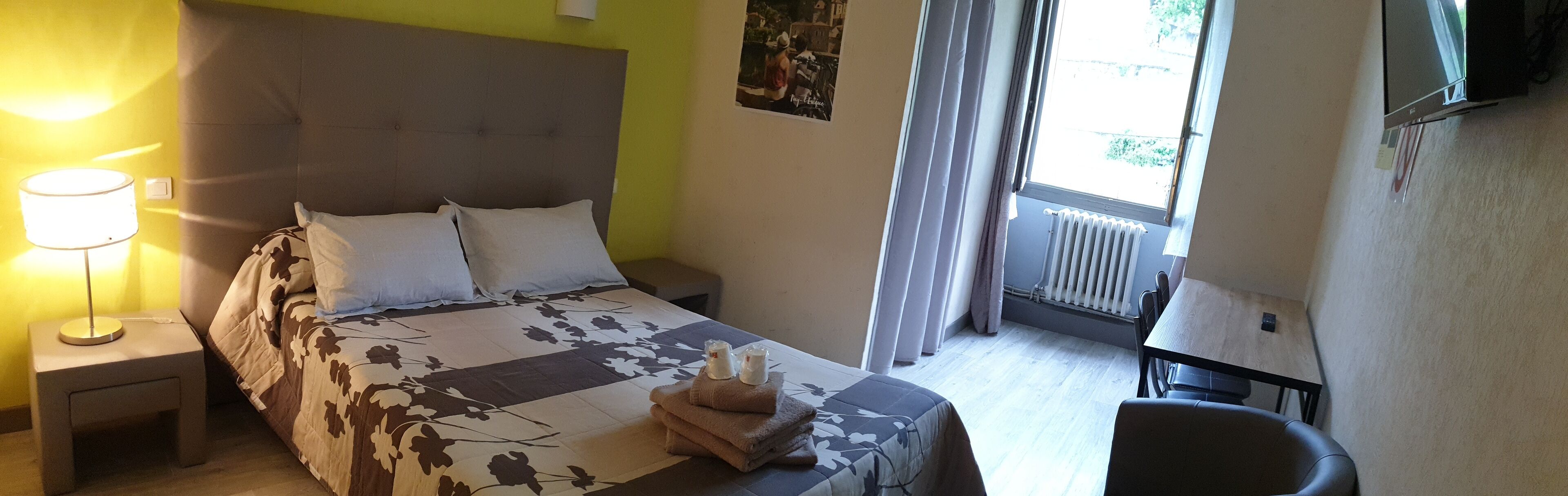 A hotel room with a bed, a nightstand, a table, and a chair.