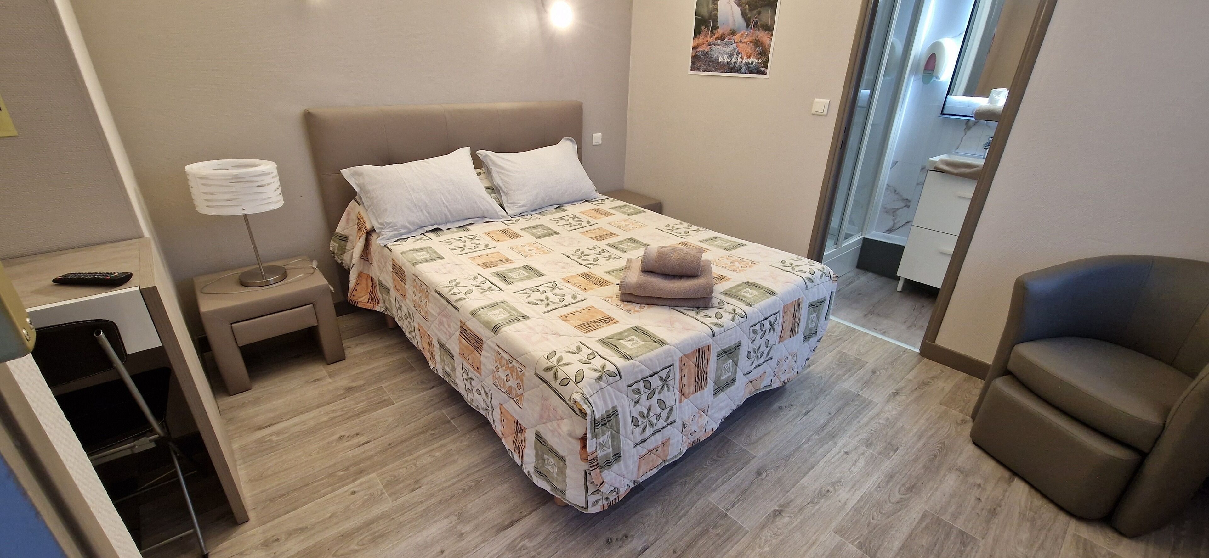 Une chambre bien rangée, avec un lit, une table de chevet, une lampe et une chaise.
