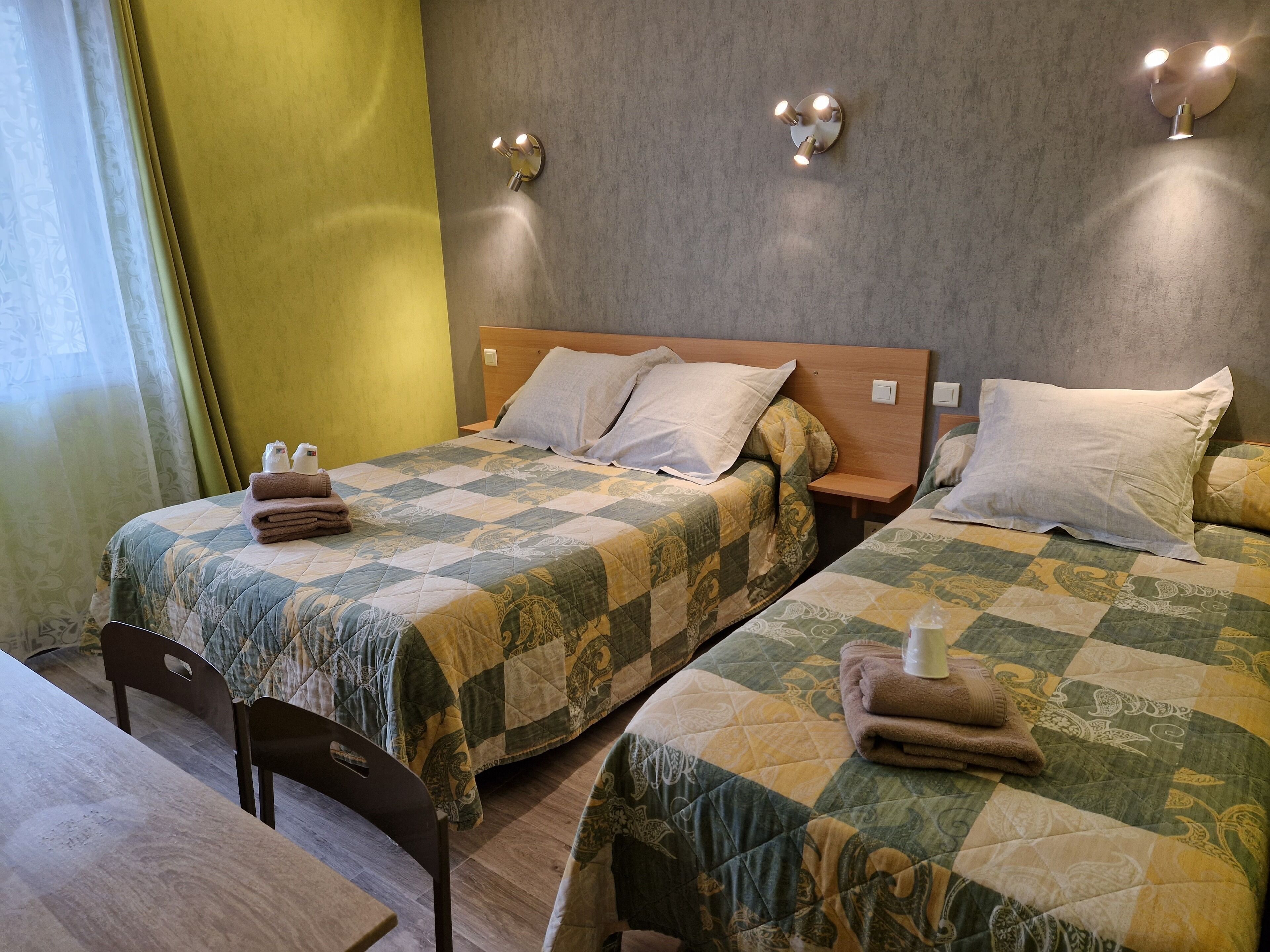 Une chambre d’hôtel avec deux lits, chacun doté d’une couvre-lit matelassé, d’une tête de lit en bois et d’une table de chevet avec une lampe.