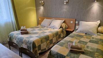 Une chambre d’hôtel avec deux lits, chacun doté d’une couvre-lit matelassé, d’une tête de lit en bois et d’une table de chevet avec une lampe.