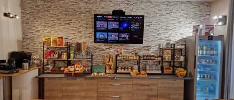 A kitchen area with a stone wall, a television mounted above the counter, and various food items and kitchen appliances.