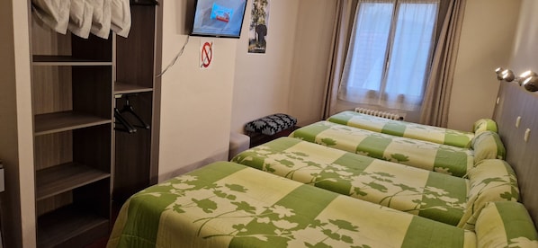 Un dormitorio con dos camas, un armario, un televisor y una ventana con cortinas.
