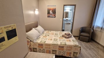 Una habitación de hotel con una cama, una silla, un espejo y un cartel en la pared.