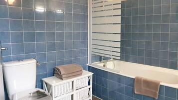 A bathroom with blue tiles, a white toilet, a white sink, and a bathtub.