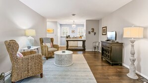 A living room with wicker furniture, a round coffee table, and a television on a cabinet.