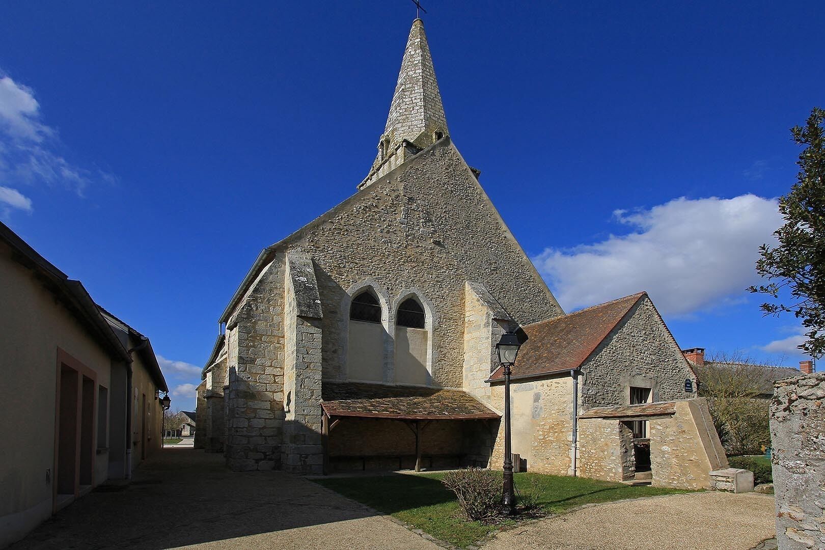 A stone church with a pointed steeple and arched windows.