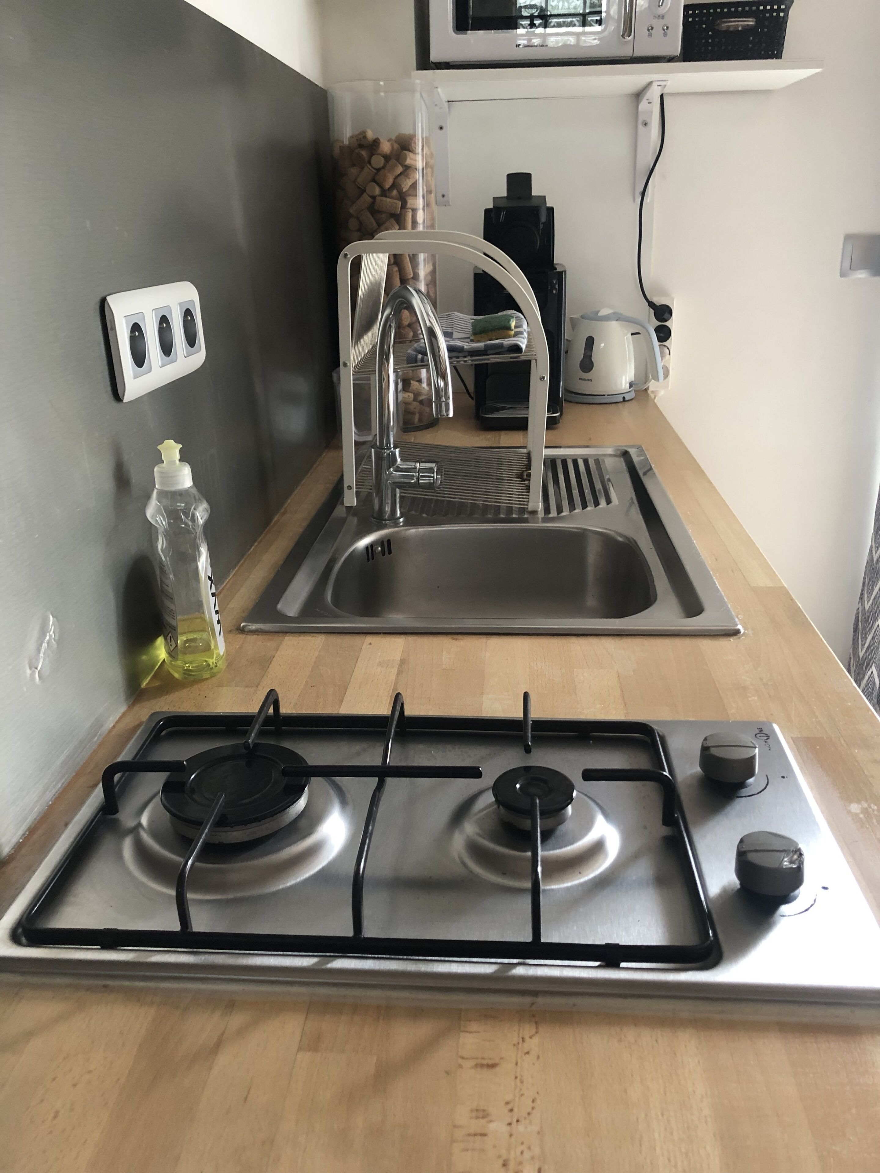 A kitchen with a stainless steel sink, a gas stove, and a microwave above the sink.
