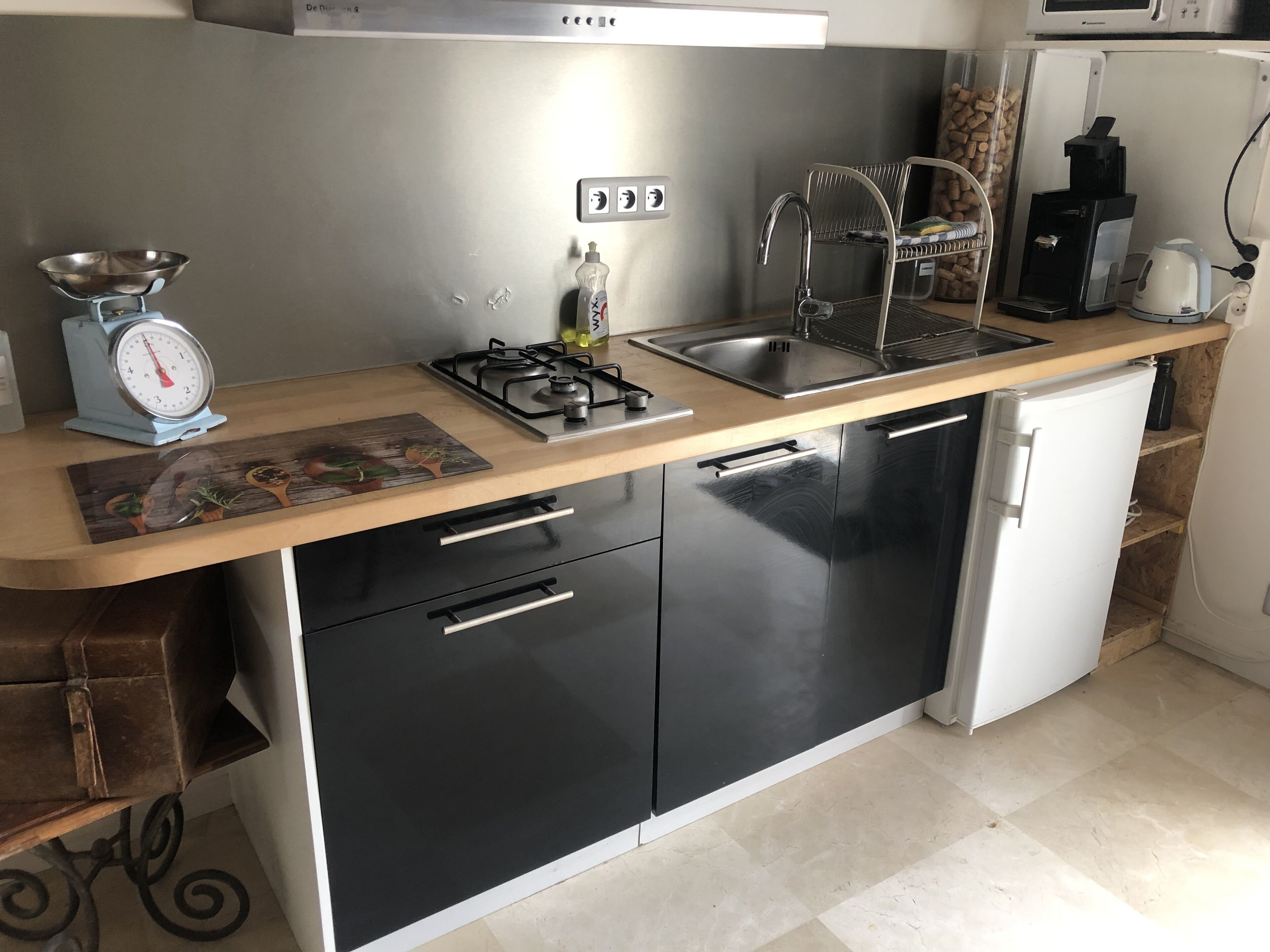 A compact kitchen with a gas stove, sink, and a small refrigerator.