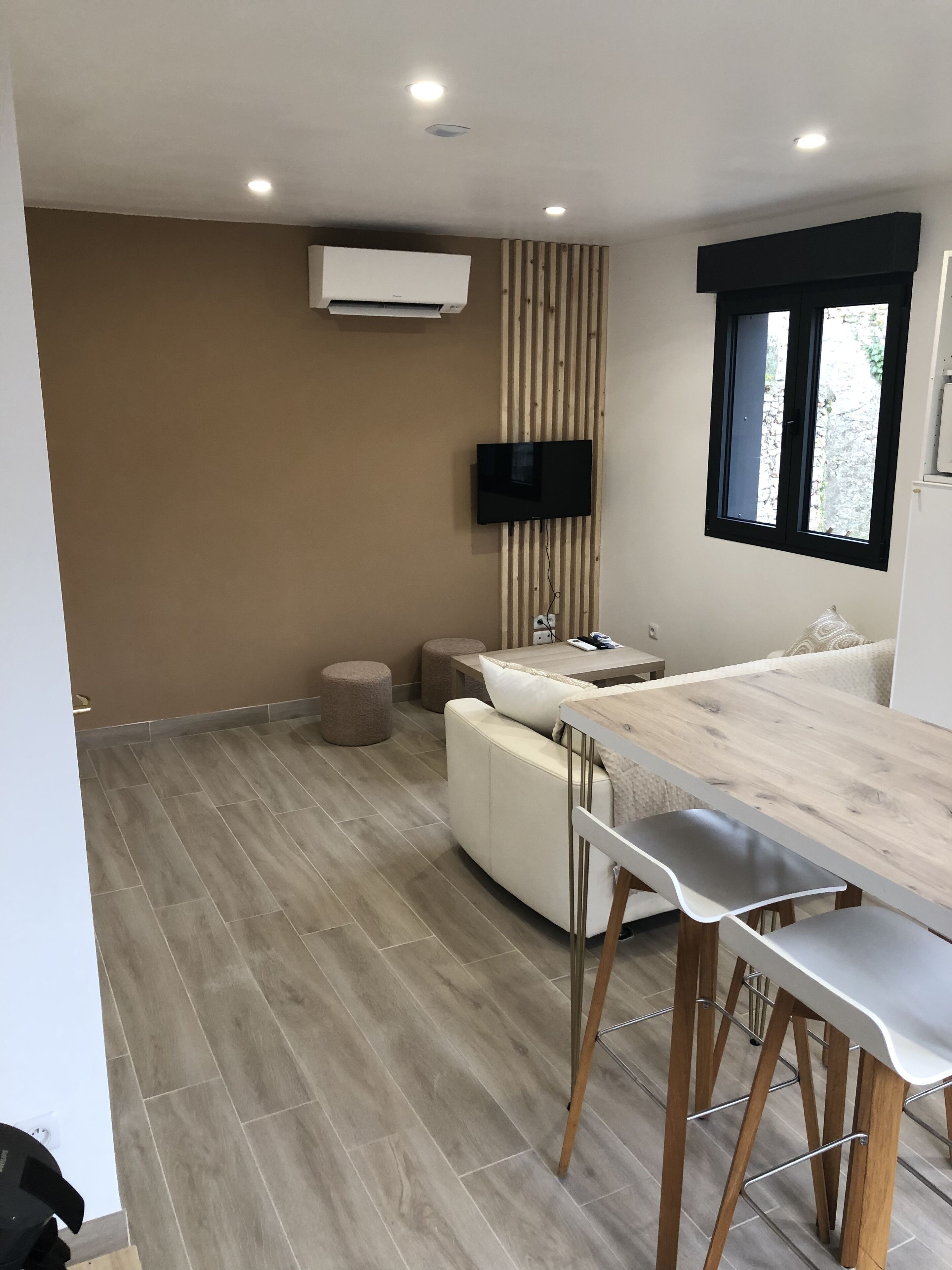 Une cuisine moderne dotée d’un plan de travail en bois, d’un four encastré et d’un téléviseur fixé au mur.