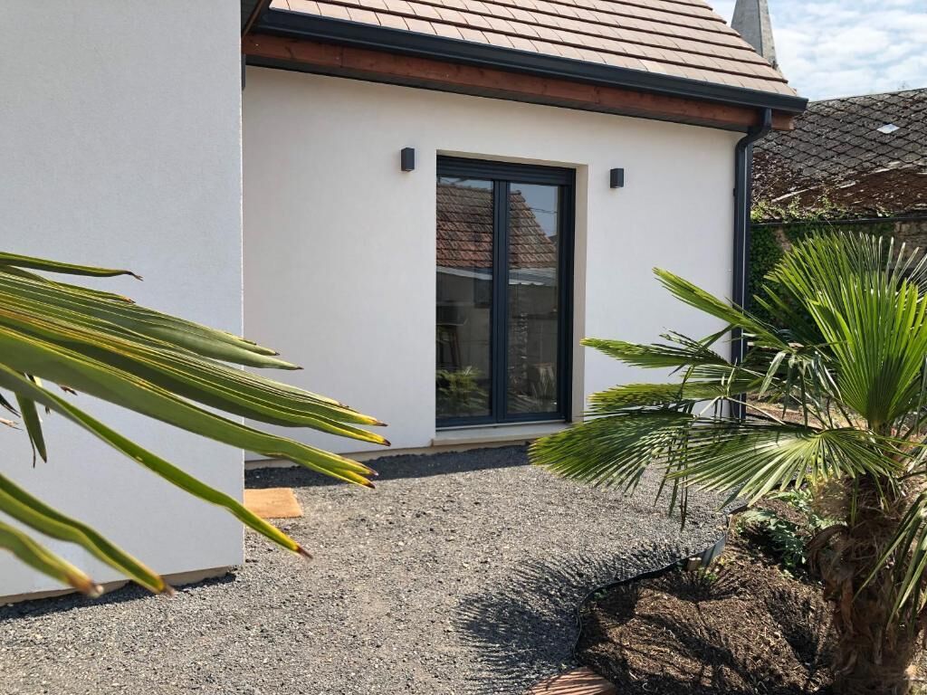 A modern house with a white exterior, a black door, and a gravel driveway.