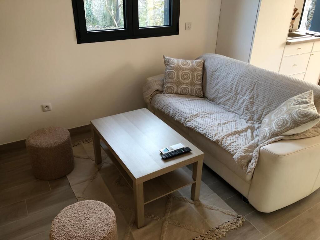 Ein Wohnzimmer mit einem beigefarbenen Sofa, einem Holztisch und einem kleinen Hocker.