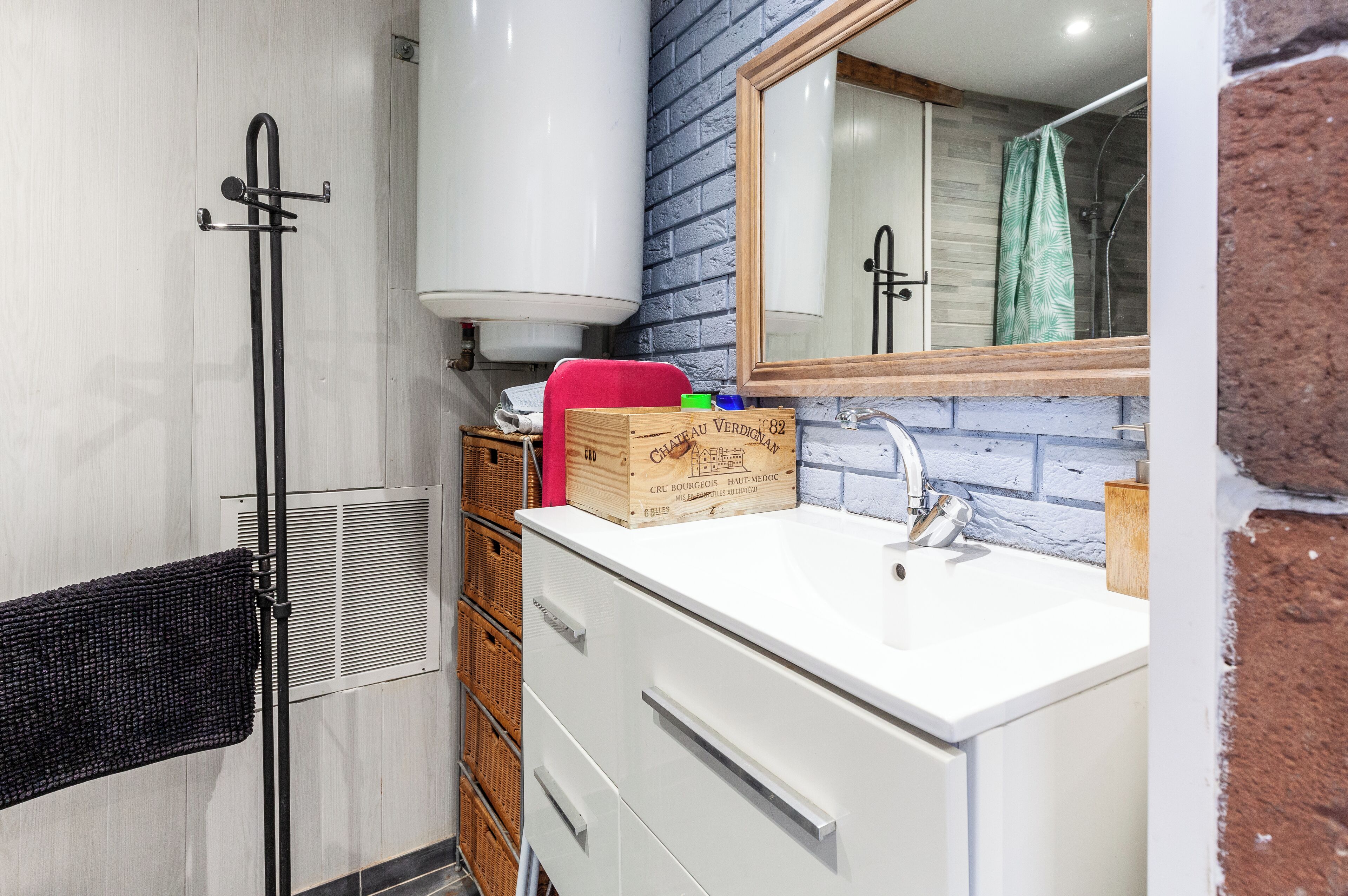 Une salle de bain avec un lavabo blanc, un miroir, une douche et un porte-serviettes.