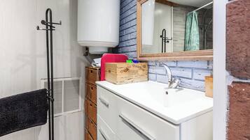 Une salle de bain avec un lavabo blanc, un miroir, une douche et un porte-serviettes.