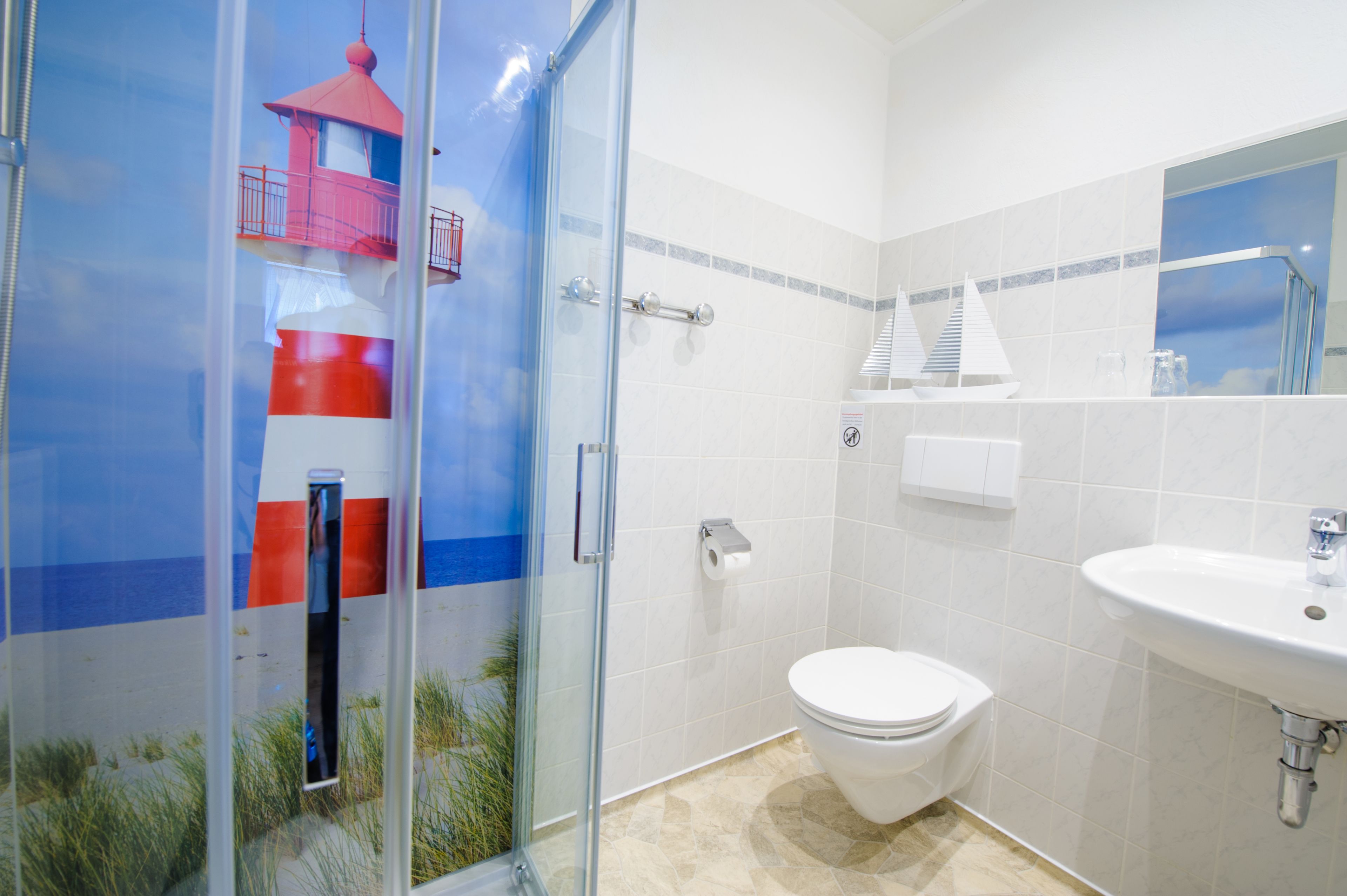 A bathroom with a glass shower enclosure, a white toilet, and a sink.
