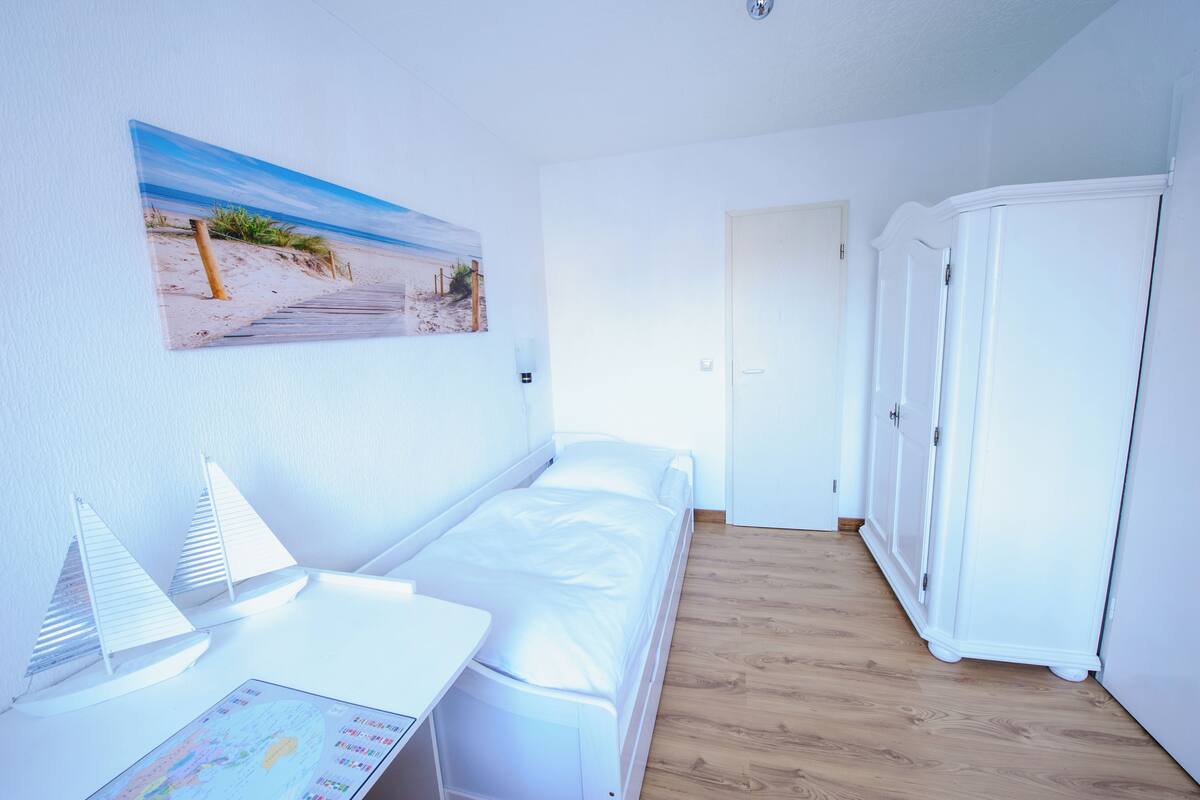 Une chambre avec un lit, un bureau, une carte et une armoire.