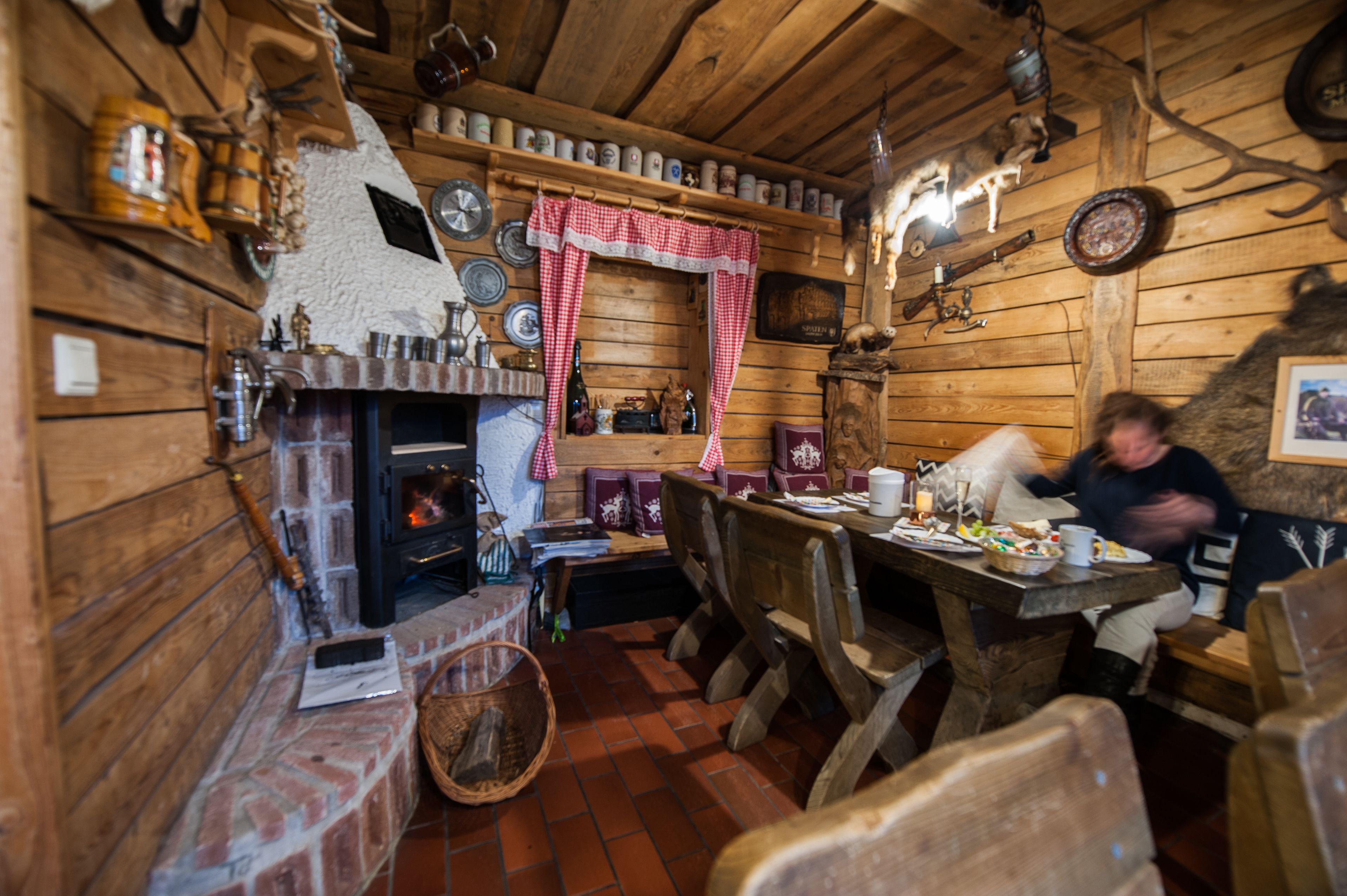 Ein rustikales Holzinterieur mit Kamin, Holzmöbeln und verschiedenen Dekorationselementen.