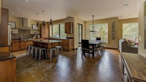 A spacious kitchen with a central island, bar stools, and a dining area with a table and chairs. - Bend River Retreat (Bend)