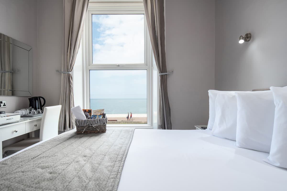 Habitación de hotel con una ventana grande, una cama, un escritorio y una silla.