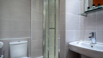 A modern bathroom with a glass shower enclosure, a white sink, and a toilet.
