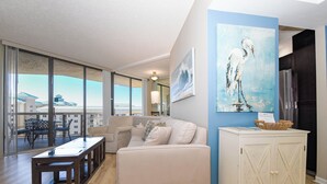 A spacious living area with a large window, a sofa, a coffee table, and a cabinet.