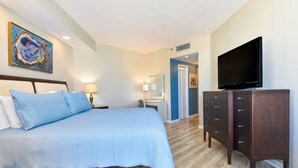 A hotel room with a bed, a dresser, a television, and a desk with a chair.
