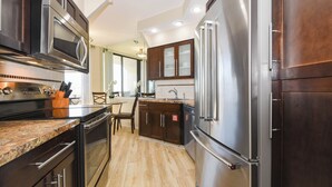 A modern kitchen with stainless steel appliances, dark wood cabinets, and a granite countertop.