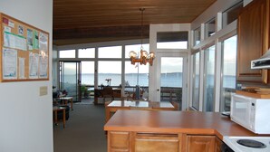Una cocina con armarios de madera, una estufa blanca y vistas al mar a través de amplios ventanales.