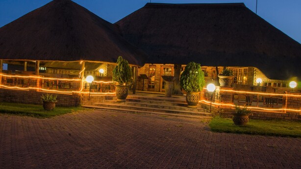 A building with a brick facade and a thatched roof, featuring a paved entrance and potted plants. - Pepe Piatto (Dipaleseng)