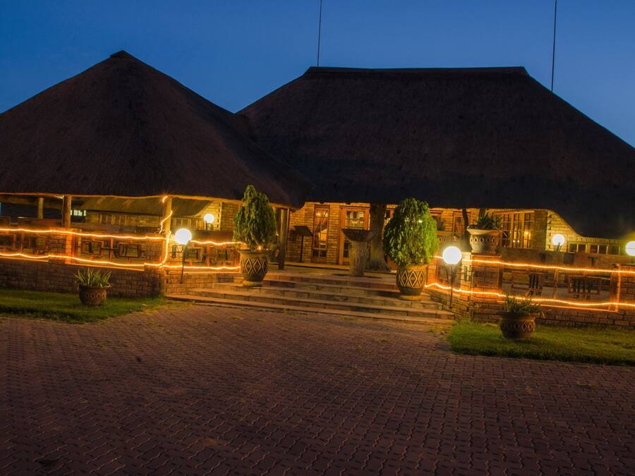 A building with a brick facade and a thatched roof, featuring a paved entrance and potted plants.