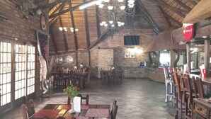A rustic interior with exposed wooden beams, a brick wall, and a chandelier. Tables and chairs are arranged for dining. - Pepe Piatto (Dipaleseng)