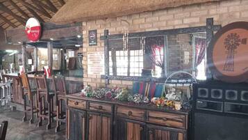 Un área de bar rústica con muebles de madera, techo de paja y decoración con molino.