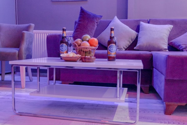 A modern living room with a sofa, a coffee table, and a basket of fruits and bottles. - Chez Bore  (Istanbul)