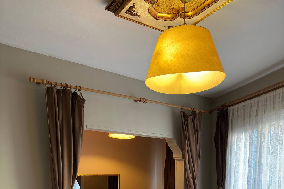 A hotel room with a bed, a chair, a table, and a large window with curtains.