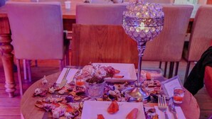 A dining table with a decorative glass lamp, a small vase with flowers, and a menu sign. - Chez Bore  (Istanbul)