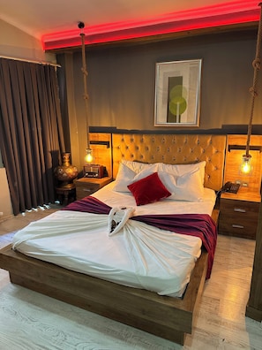 A neatly made bed with a white comforter and a red pillow, a bedside table with a lamp, and a framed picture on the wall. - Chez Bore  (Istanbul)