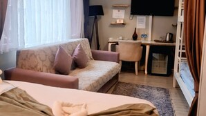 A hotel room with a bed, a sofa, a desk, a television, and an air conditioning unit. - Chez Bore  (Istanbul)
