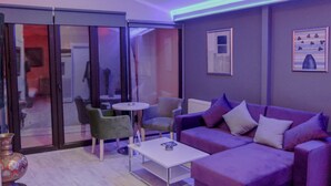 A modern living room with a purple sofa, green armchair, and a small white table. - Chez Bore  (Istanbul)
