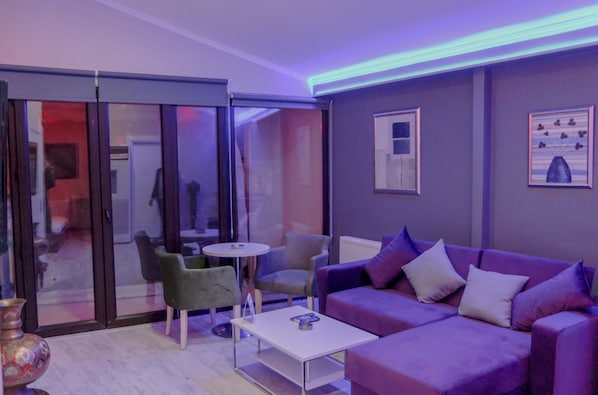A modern living room with a purple sofa, green armchair, and a small white table. - Chez Bore  (Istanbul)