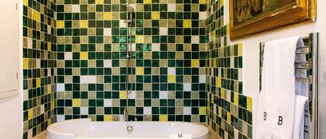 A bathroom with a bathtub, a shower, and a tiled wall.