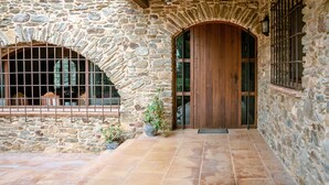 A stone building with a wooden door and a window with metal bars.